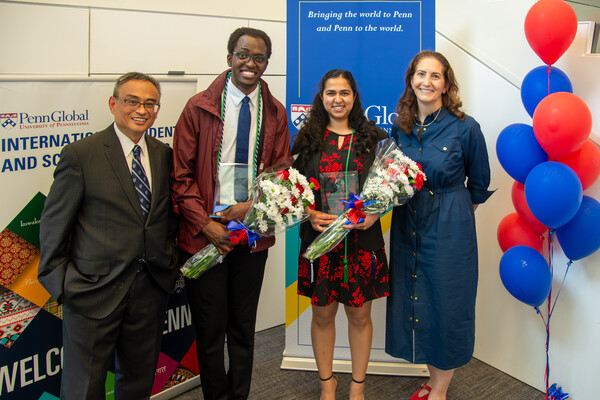 Rudie Altamirano, David Kato, Aishwarya Pawar and Amy Gadsden stand next to a tower or red and blue balloons and in front of a sign reading Bringing the world to Penn and Penn to the world.