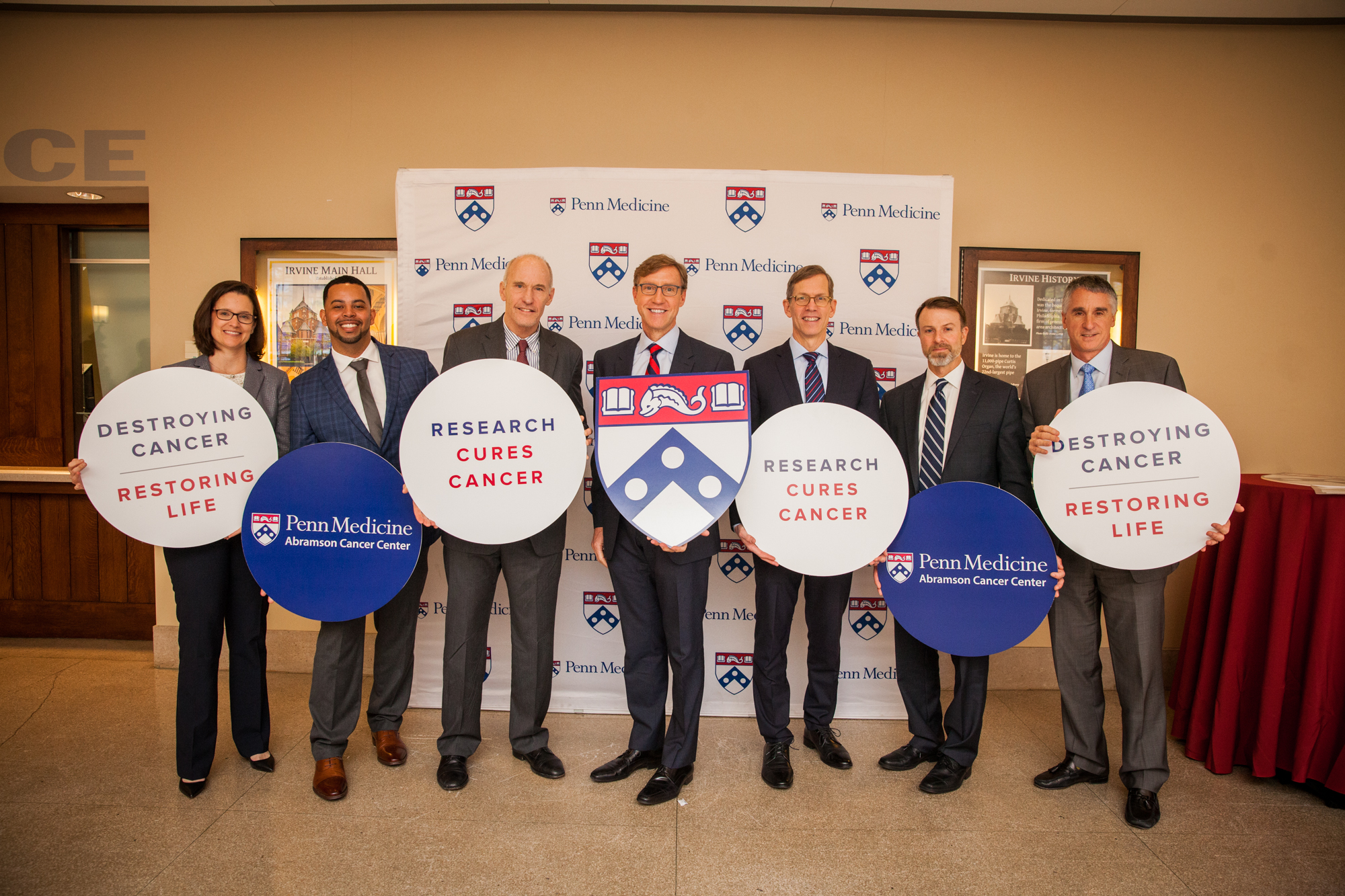 Penn Medicine researchers pose for a photo after the panel holding signs that say Destroying Cancer, Restoring Life; Research Cures Cancer, and Penn Medicine/Abramson Cancer Center