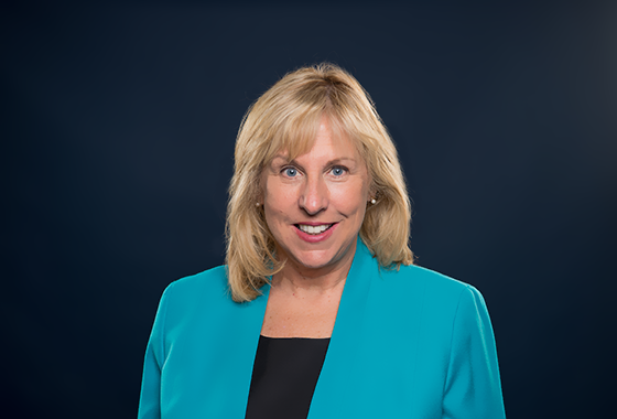 Head shot of Nancy Hodgson wearing a teal blazer with a black shirt