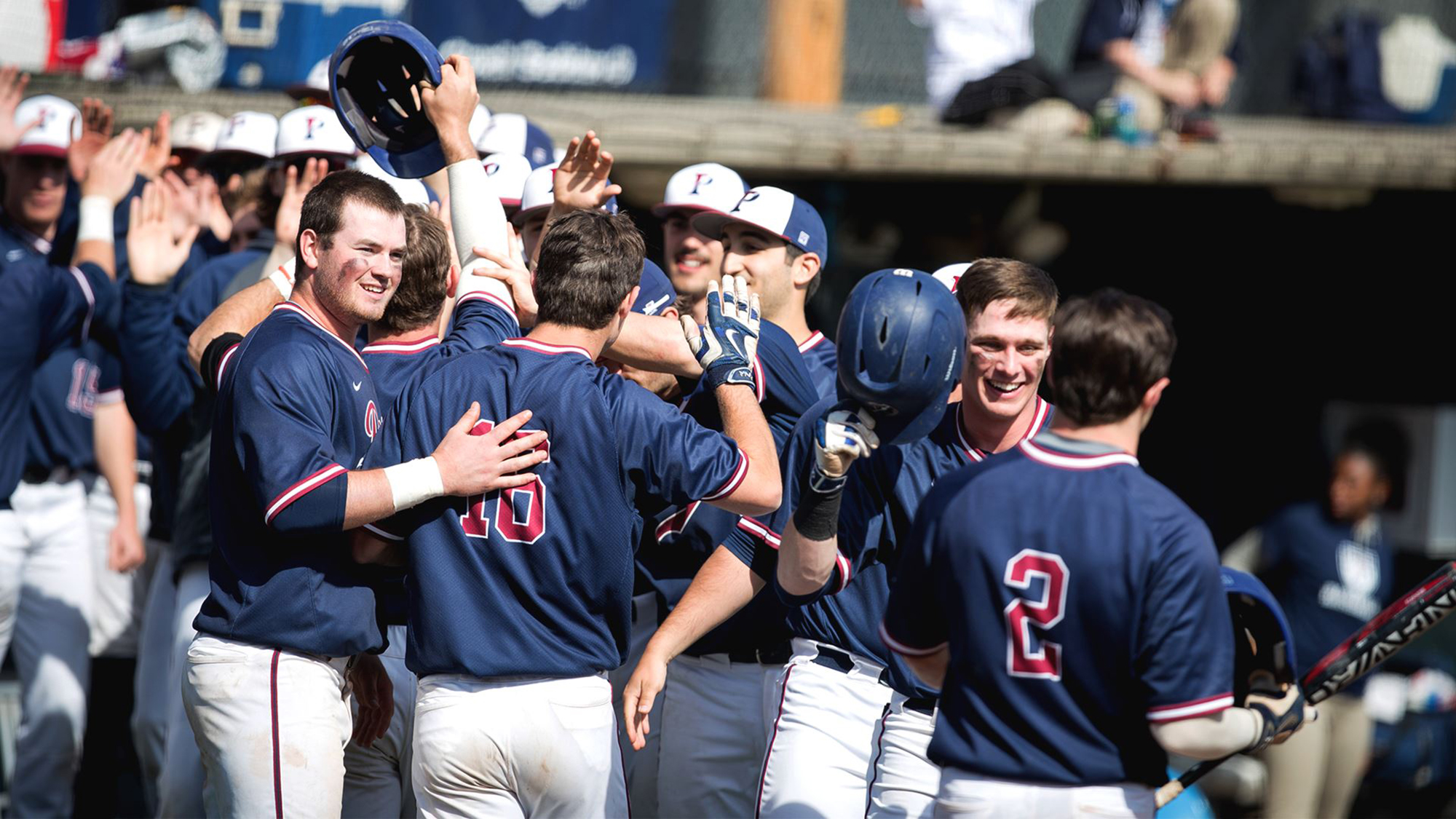 Players on the Penn baseball team celebrate and high five in a group.
