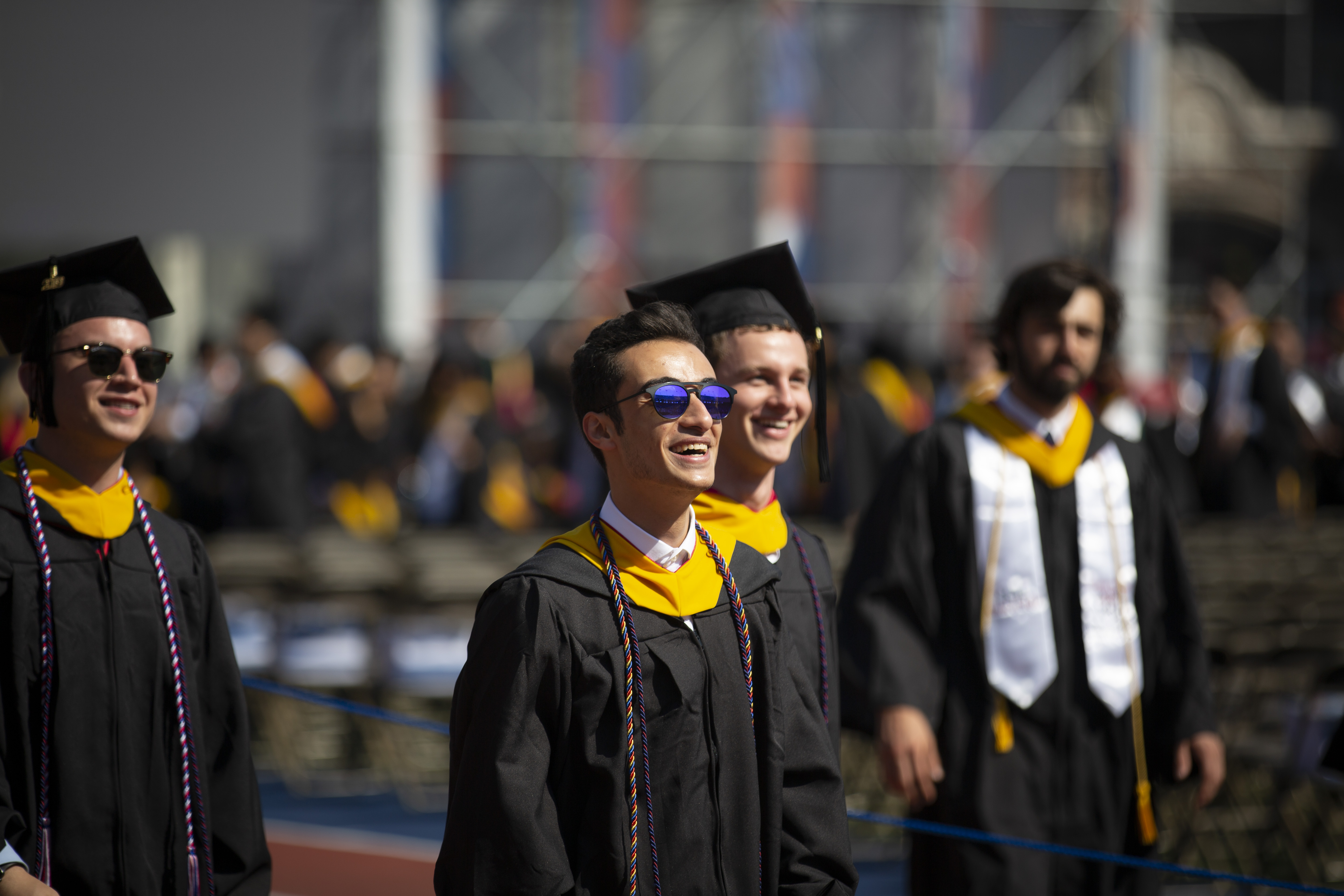 Graduating students walking into stadium, smiling