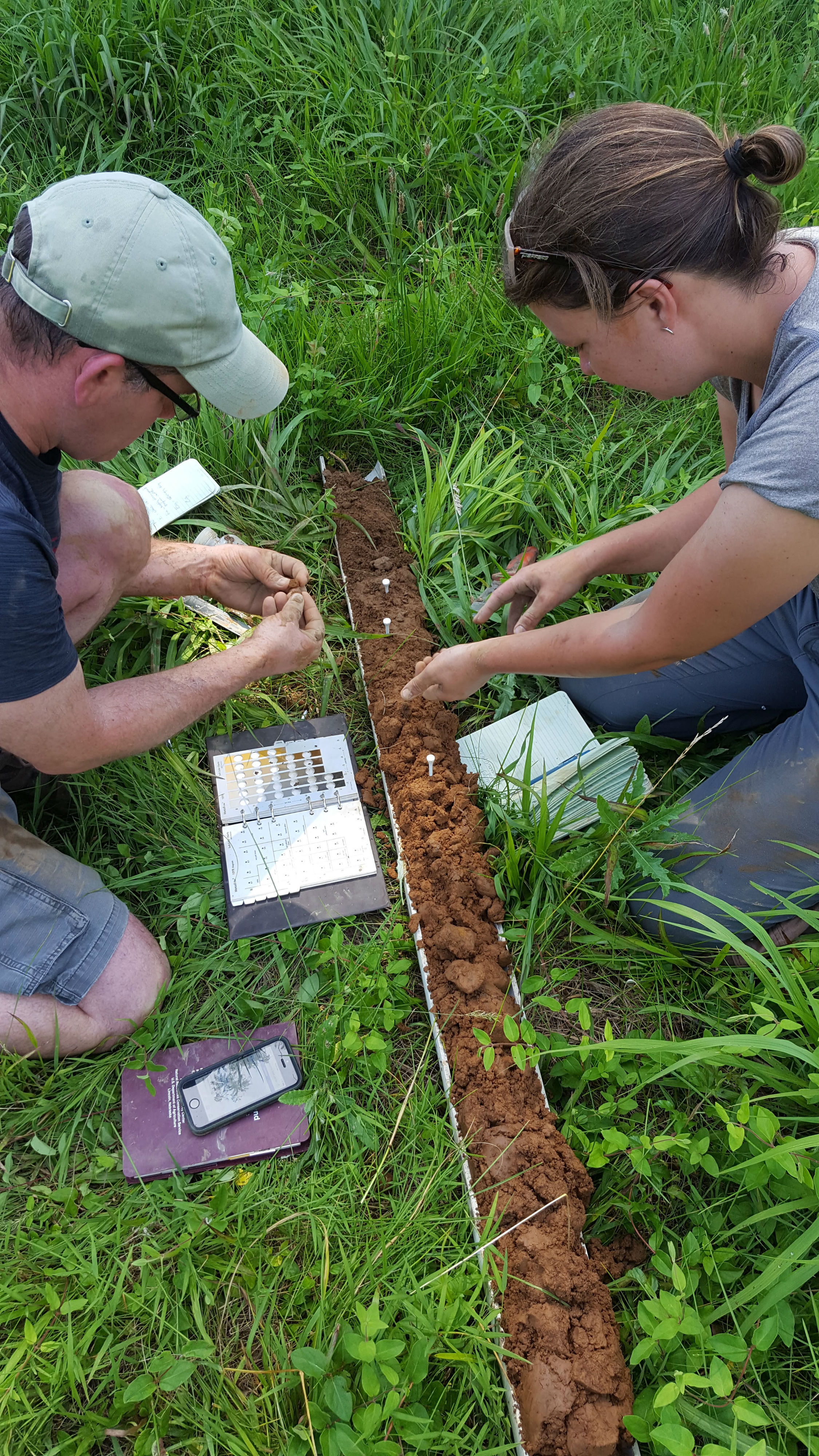 Two students examine a core of soil extracted from the ground