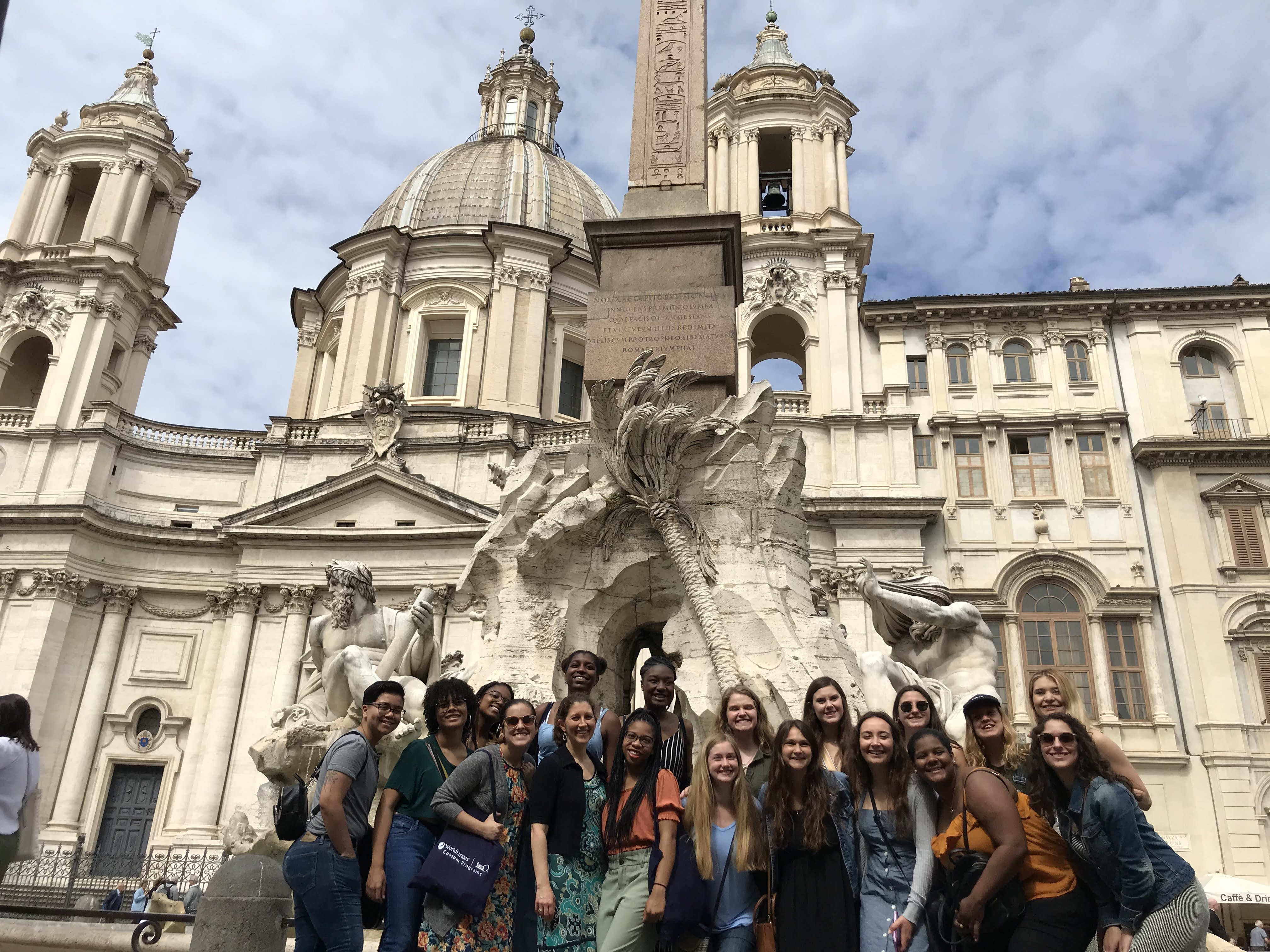 A group of people standing in front of a white statue in Rome, Italy. 