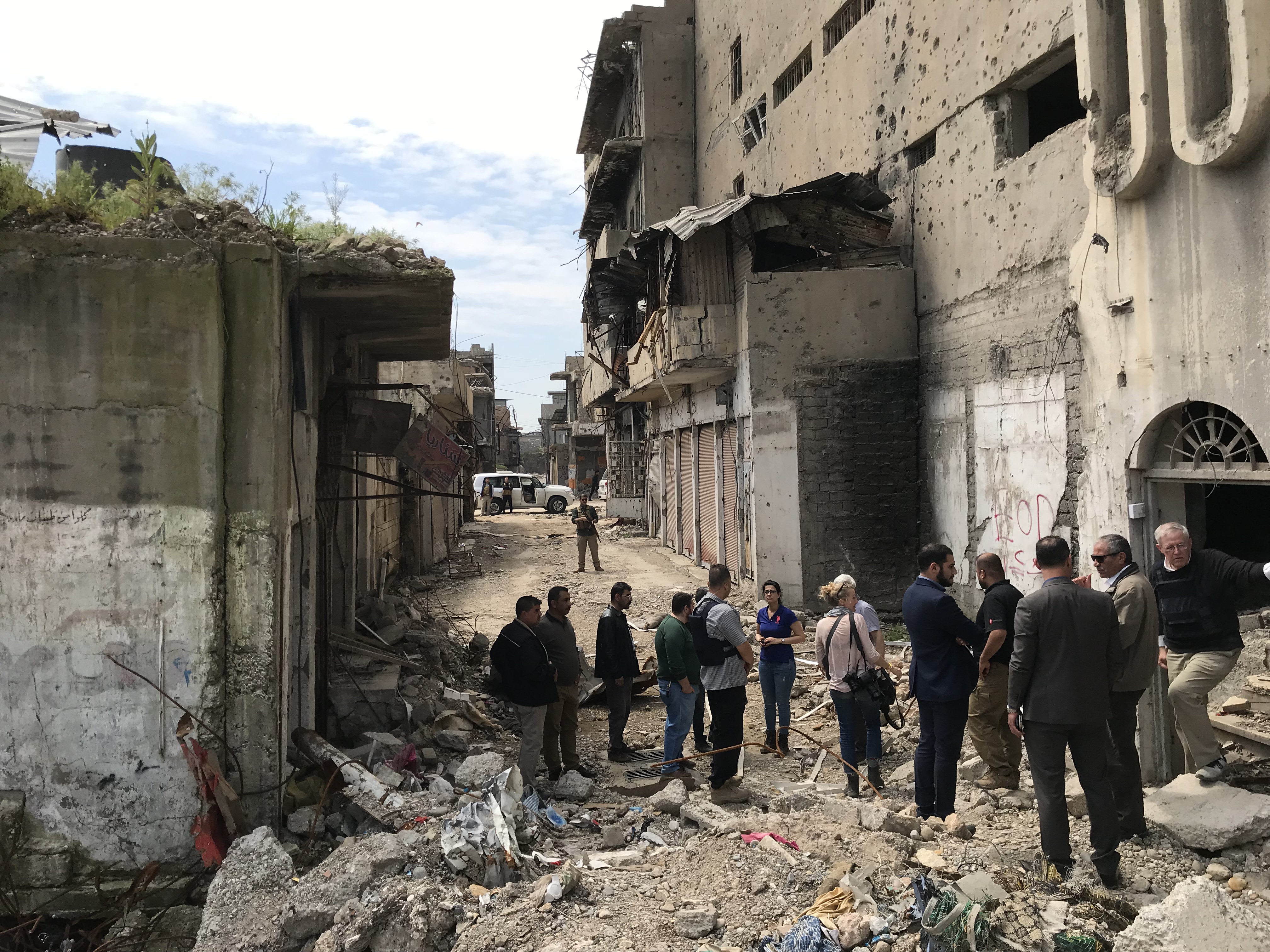 group of people surveying destroyed buildings