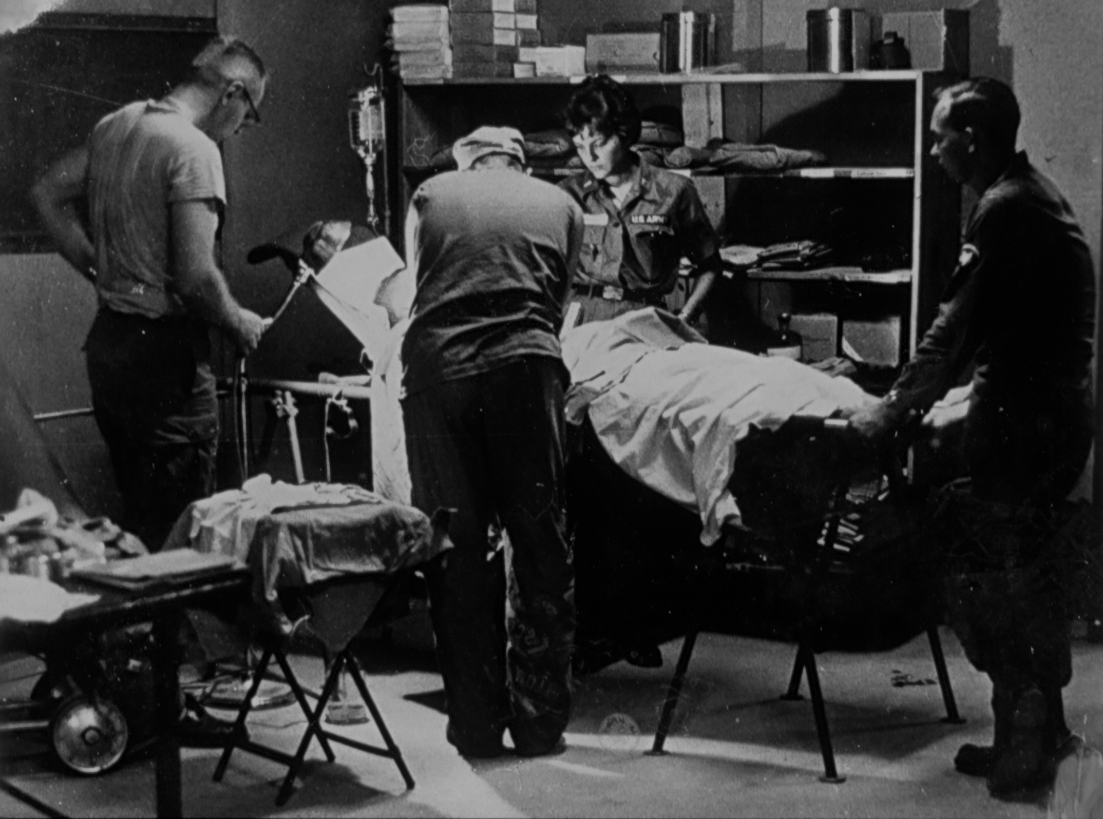 A black-and-white image of health care professionals standing around a patient in a surgical suite during the Vietnam War. 