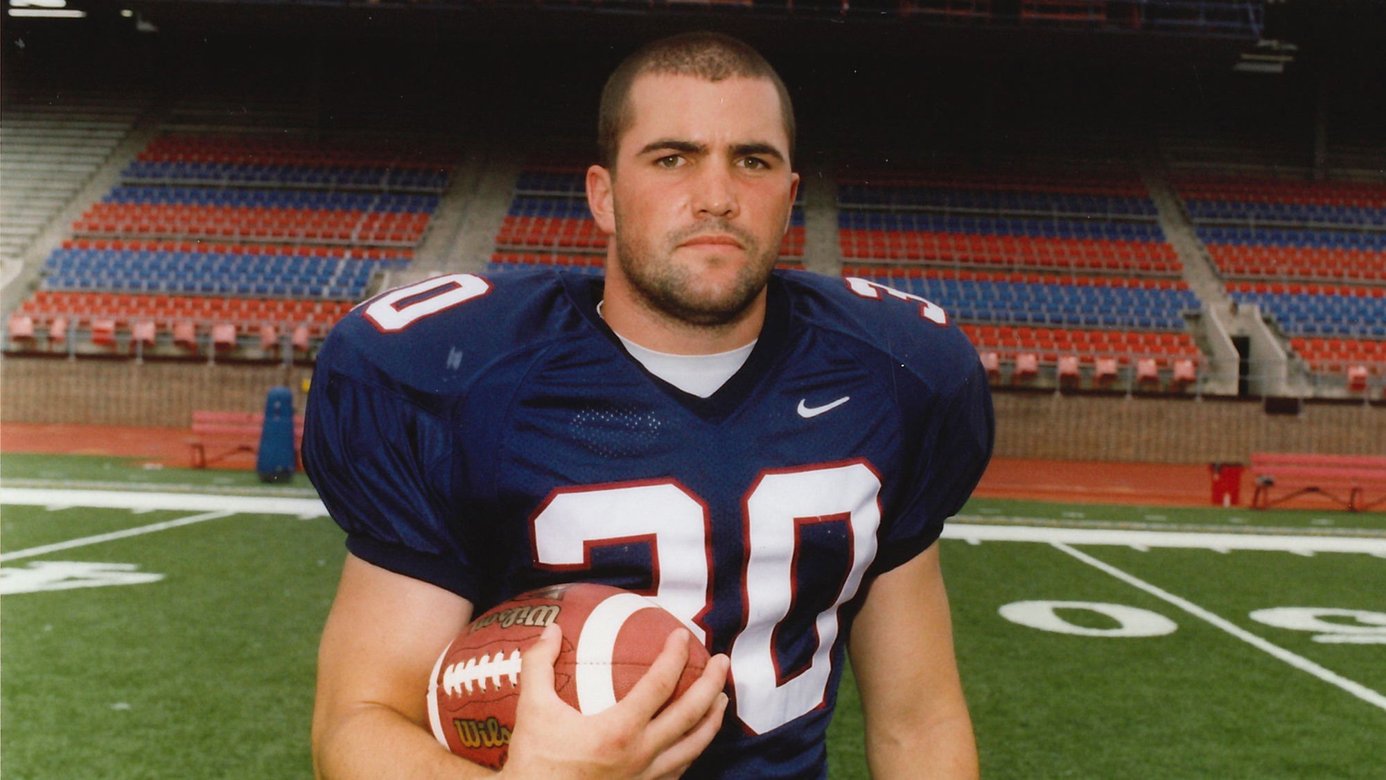During his playing days at Penn, Kevin Stefanski poses with a football and wears his jersey at Franklin Field. 