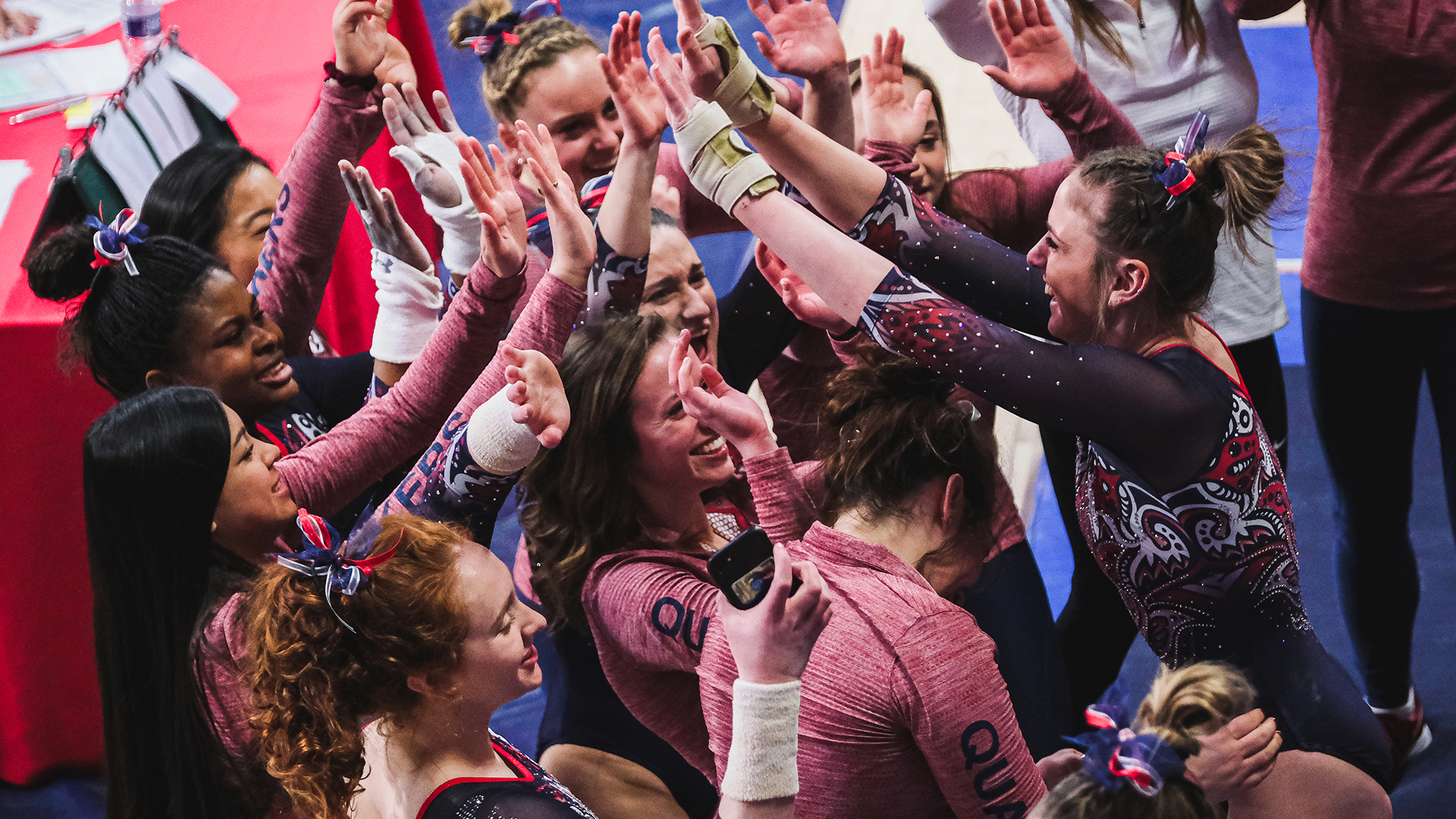 Members of the gymnastics team celebrate and high-five each other during a meet.