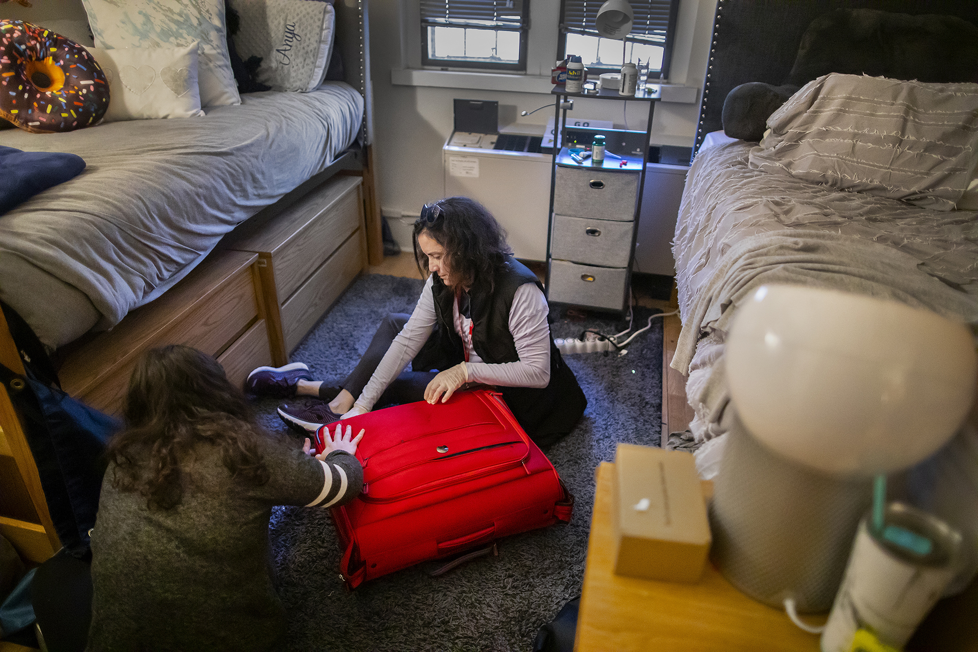 Mother and daughter packing a suitcase inside a dorm