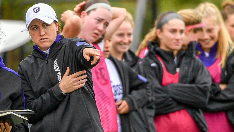 Casey Brown on far left points towards the field while members of the soccer team stand beside her on the sidelines