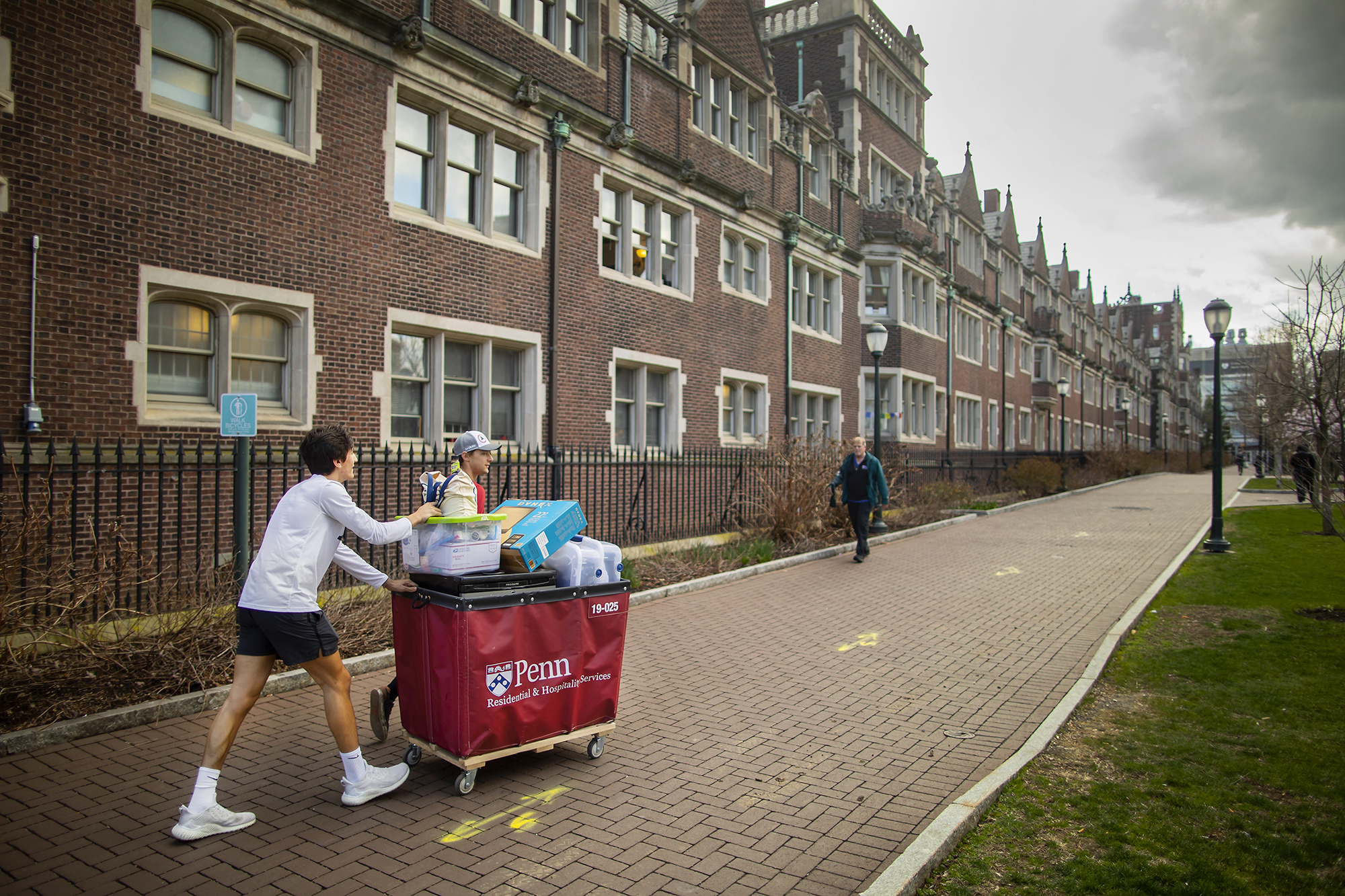 A student pushes their belongings through the Quad in a move-out cart.