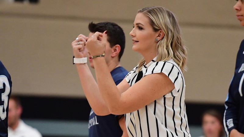 Meredith Schamun, in a white shirt with black stripes, gestures during a volleyball game.