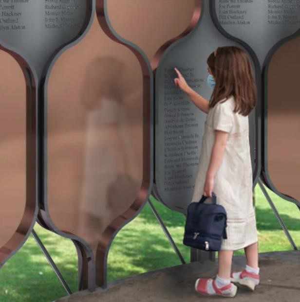 a child looks at a memorial with names etched onto a gray plate