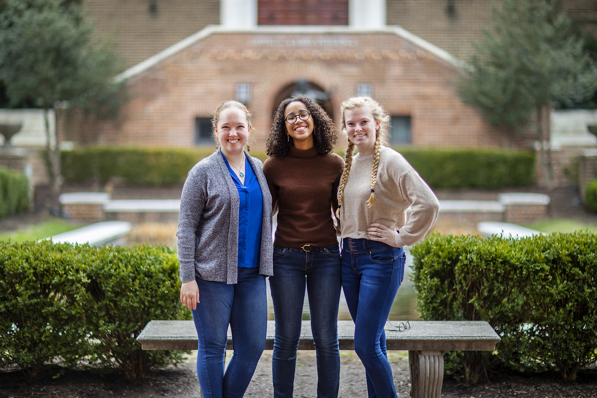 Three smiling undergraduates in a courtyard