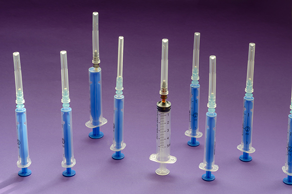 Multiple vaccine syringes standing upright on a surface.