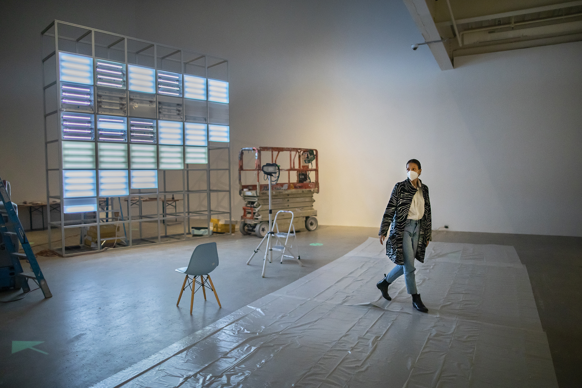 artist walking through gallery with light installation behind