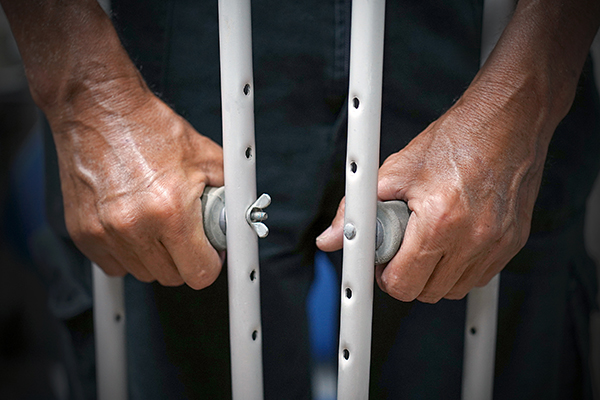 Closeup look at a Black person’s hands holding onto crutches.