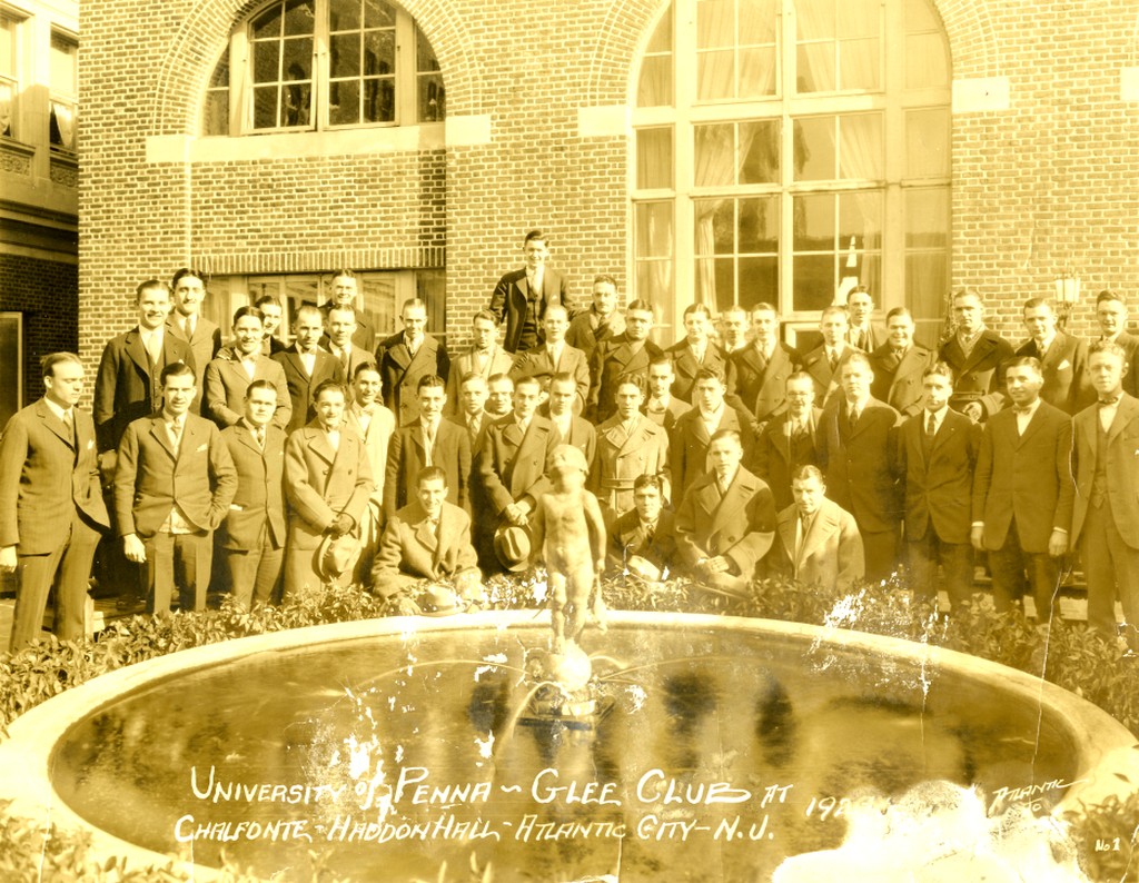 students dressed in coat and tie standing around a fountain