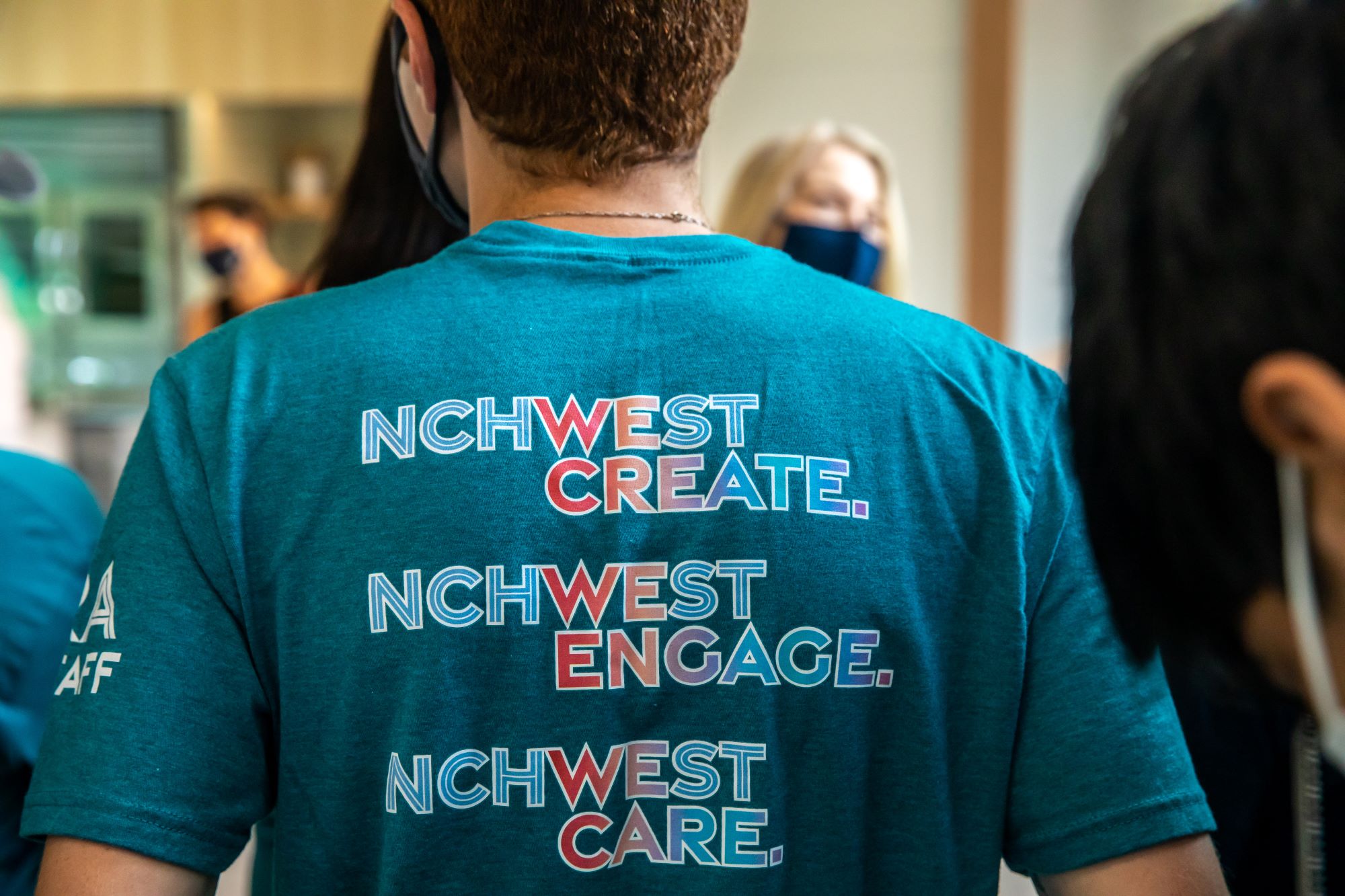 Back of T-shirt that reads NCHWest Create, NCHWest Engage, NCHWest Care