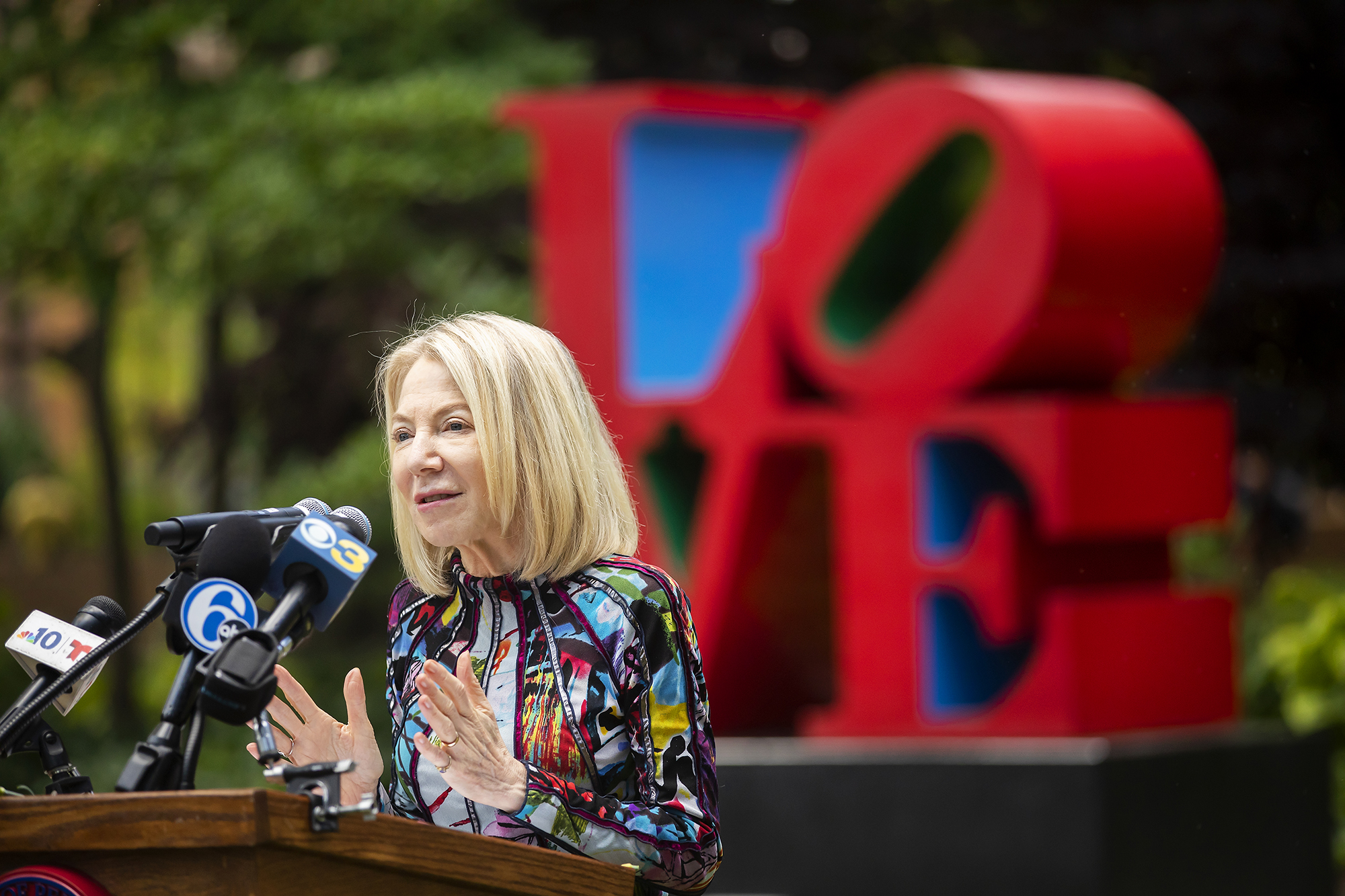 Amy Gutmann speaks at a podium in front of the LOVE statue on Penn’s campus.