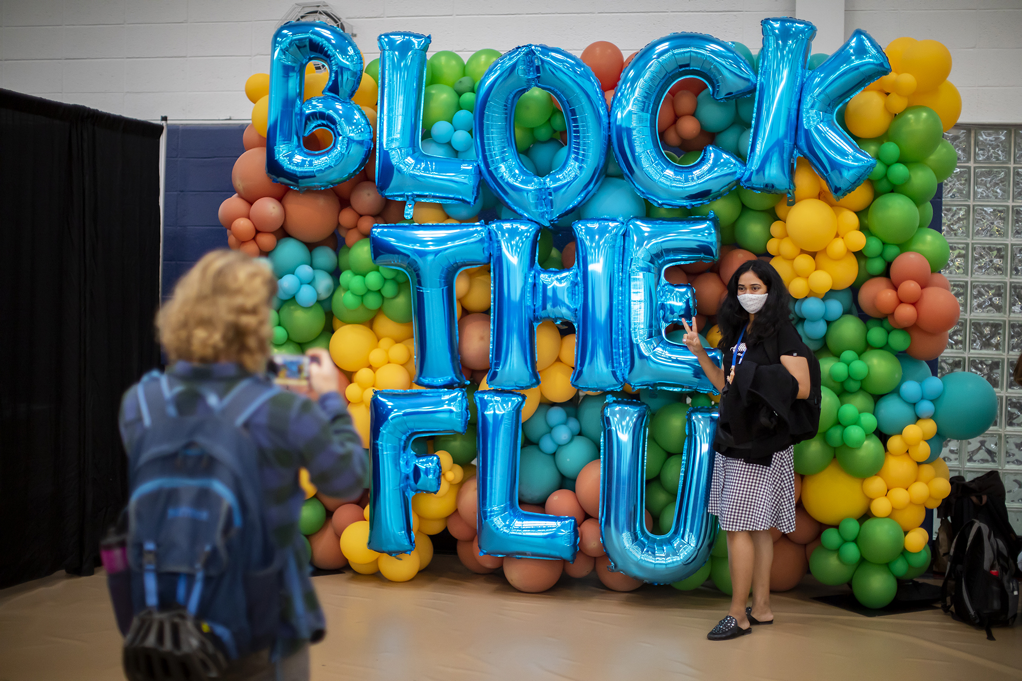 a person has their photo taken in front of balloons spelling out Block the Flu
