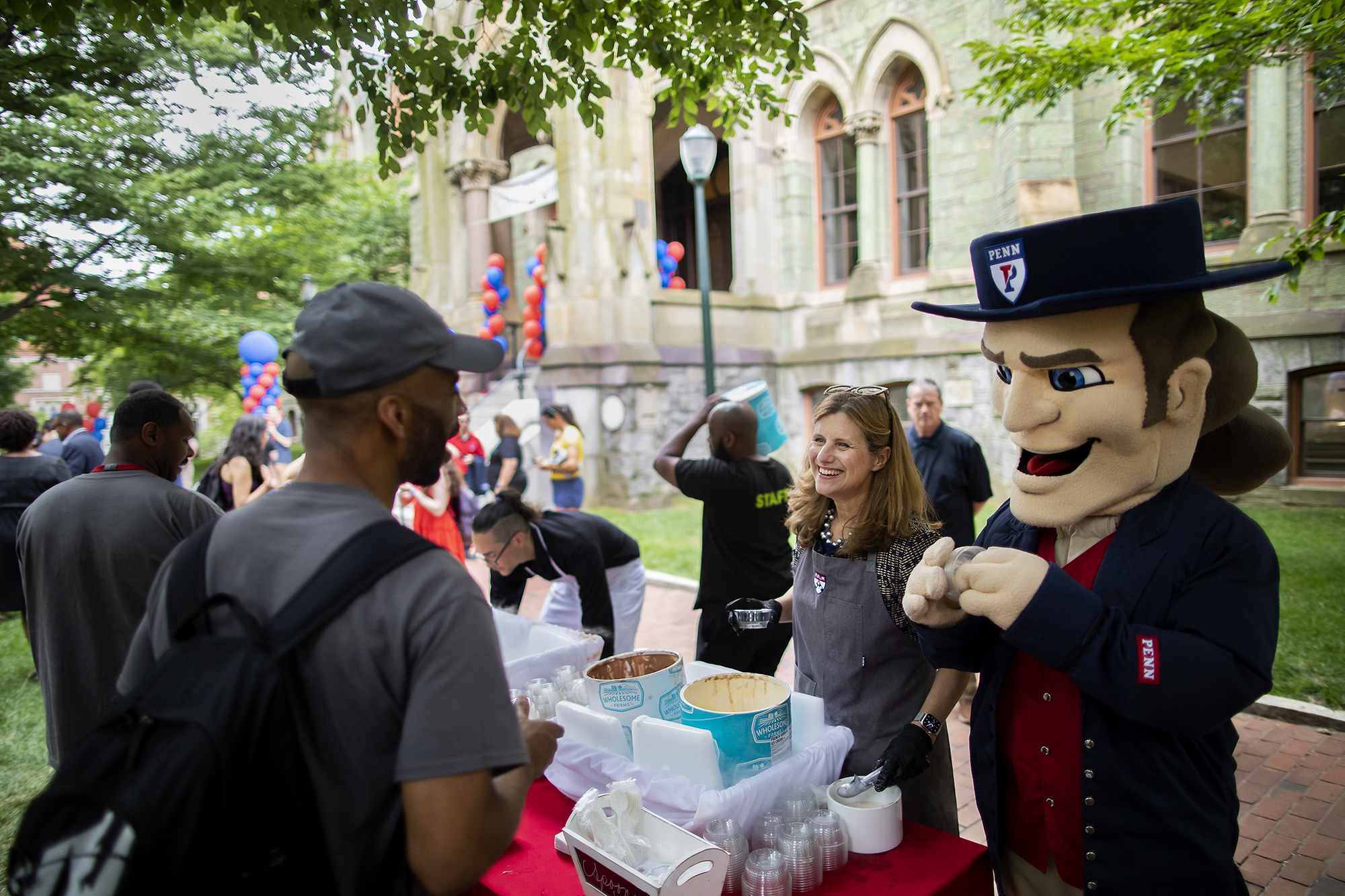 Liz Magill scoops ice cream and smiles with the Quaker mascot
