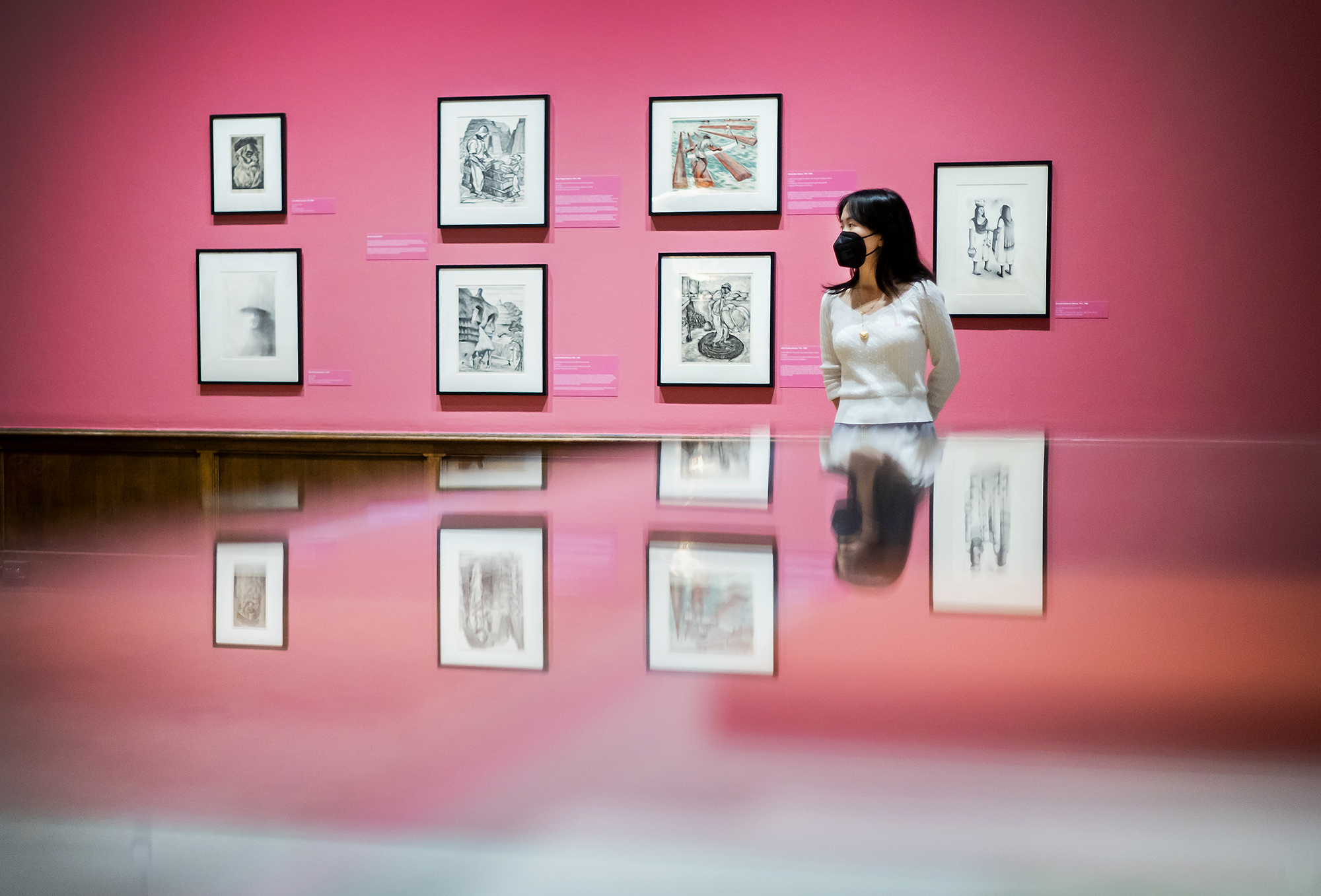 A person standing in front of a wall displaying seven works of art at the Arthur Ross Gallerry.
