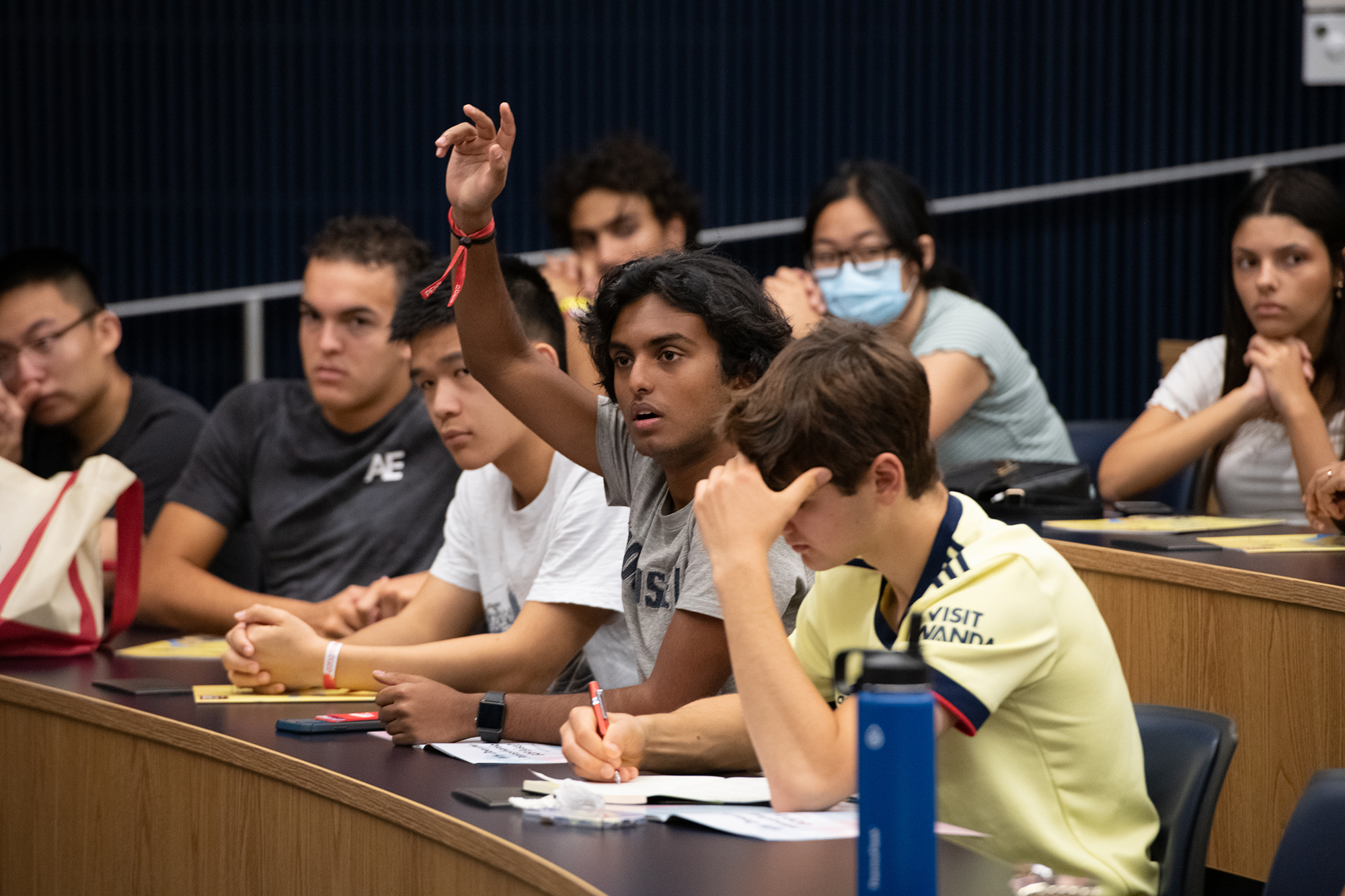 An audience member raises their hand in a lecture hall.