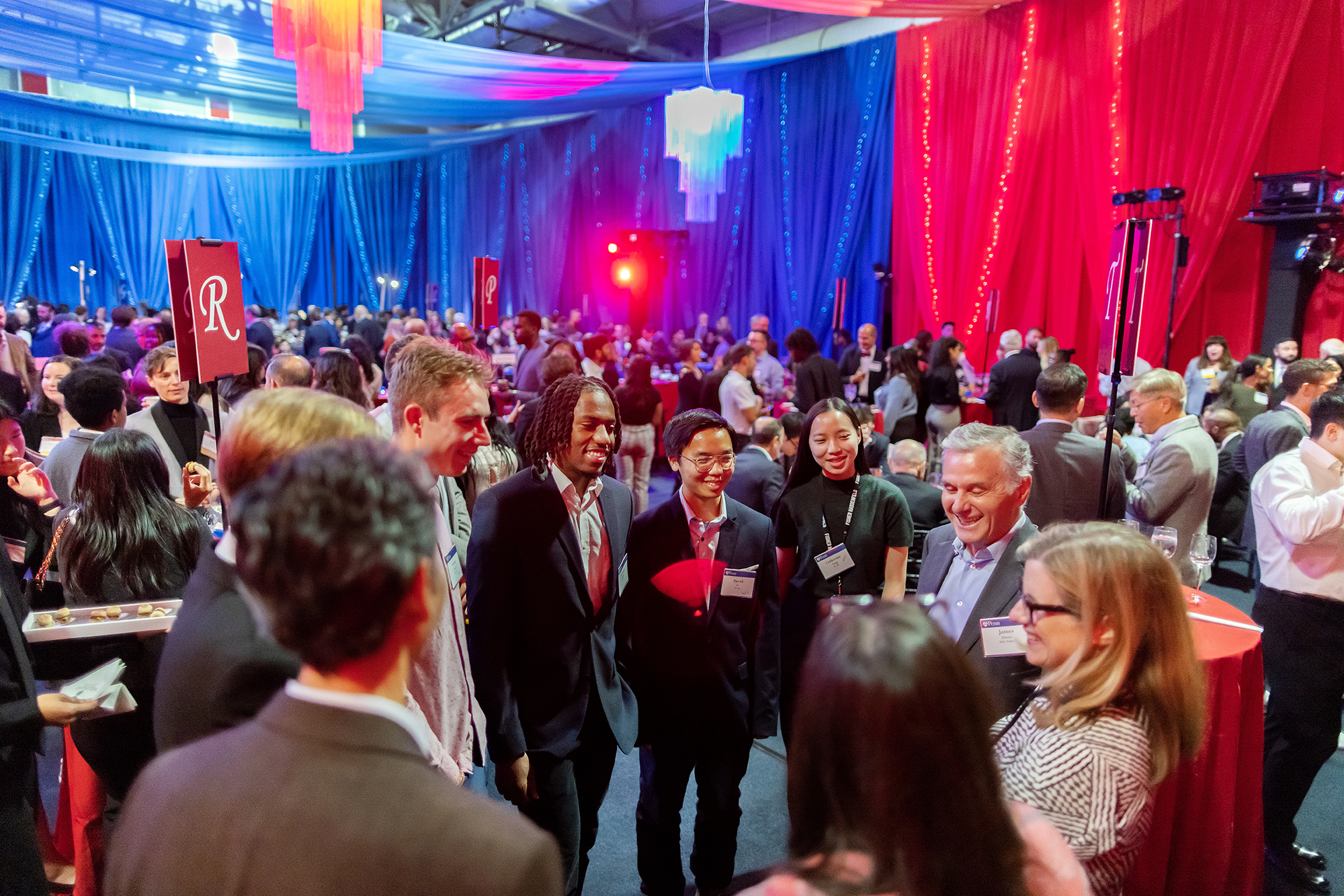 People gather inside a red-and-blue decorated gym