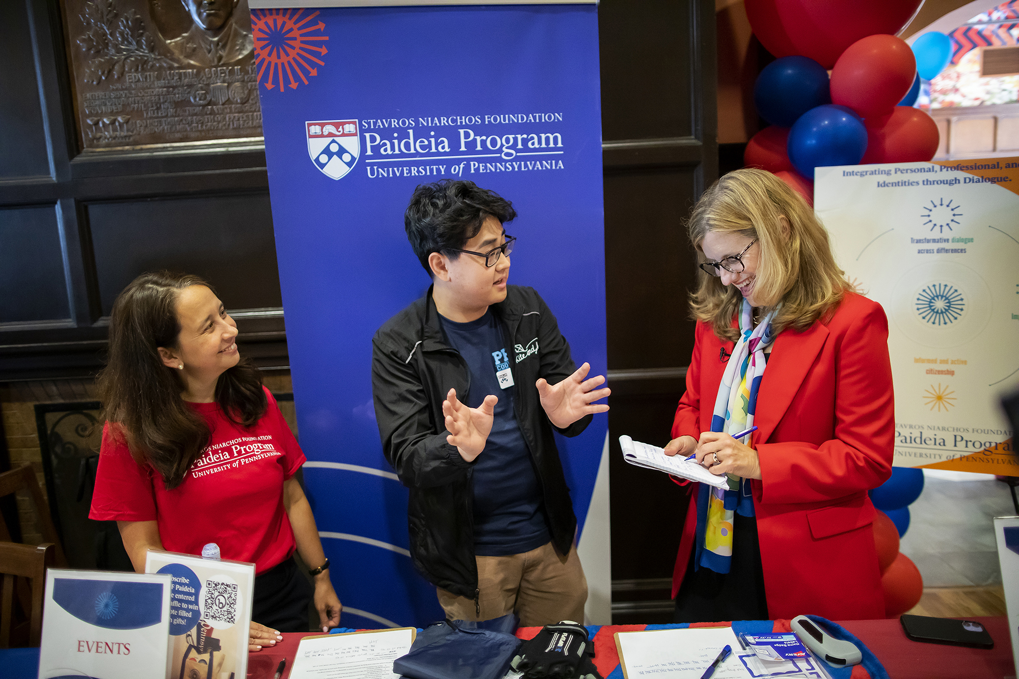 Liz Magill and two students at a table advertising Penn’s Paideia Program.