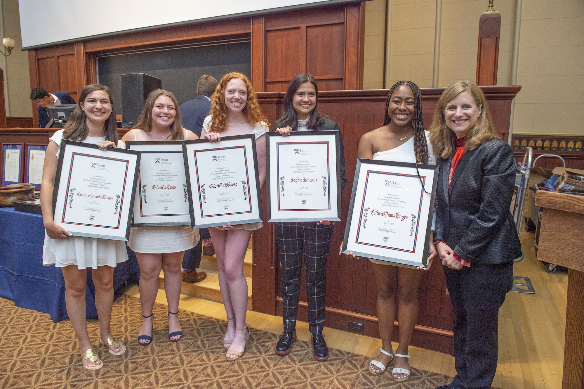 Five women hold up certificates for the President's Innovation Prize, while standing with Penn President Liz Magill