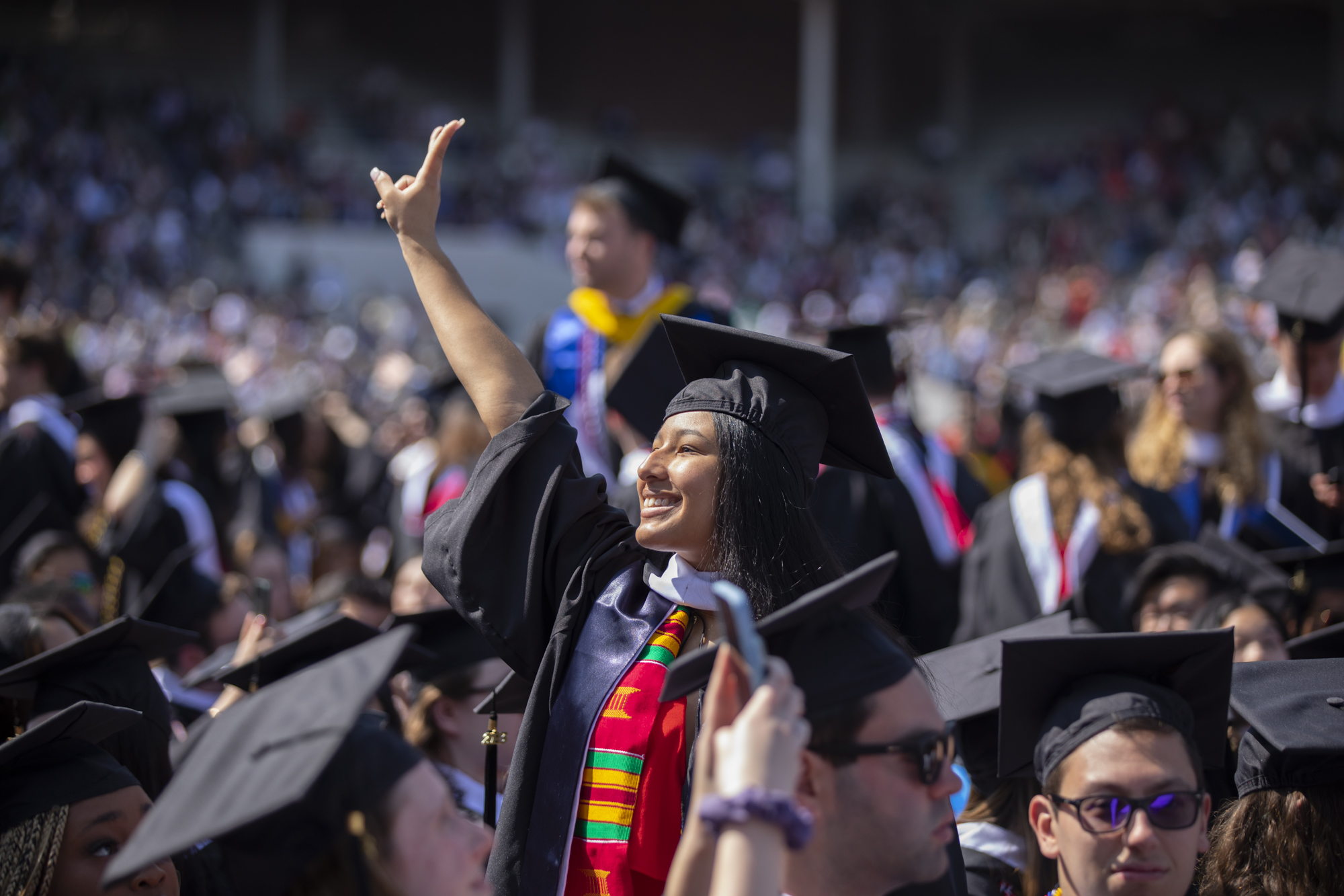 student with arm up in the air during commencement