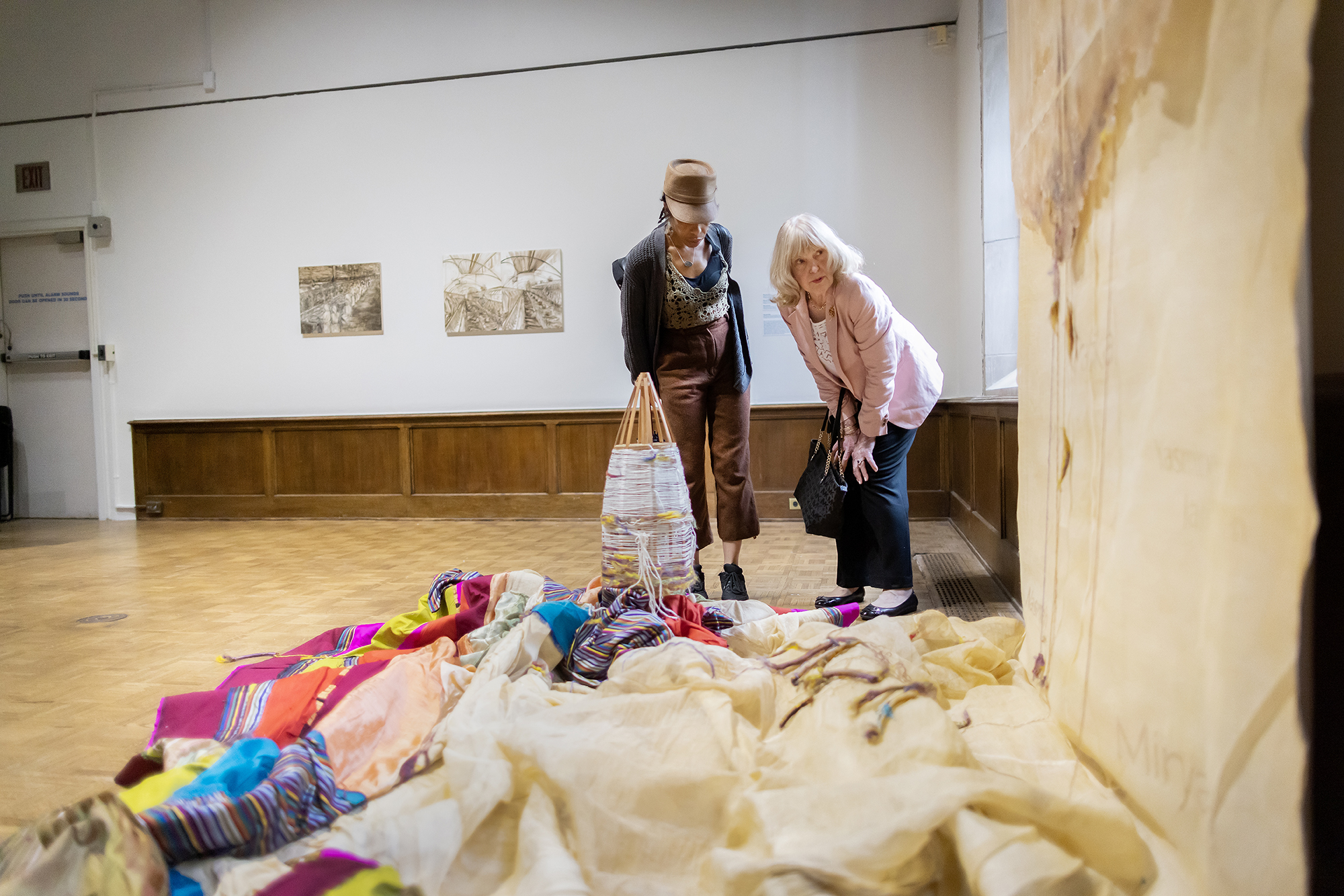 two people looking at artwork featuring fabric piled on the floor