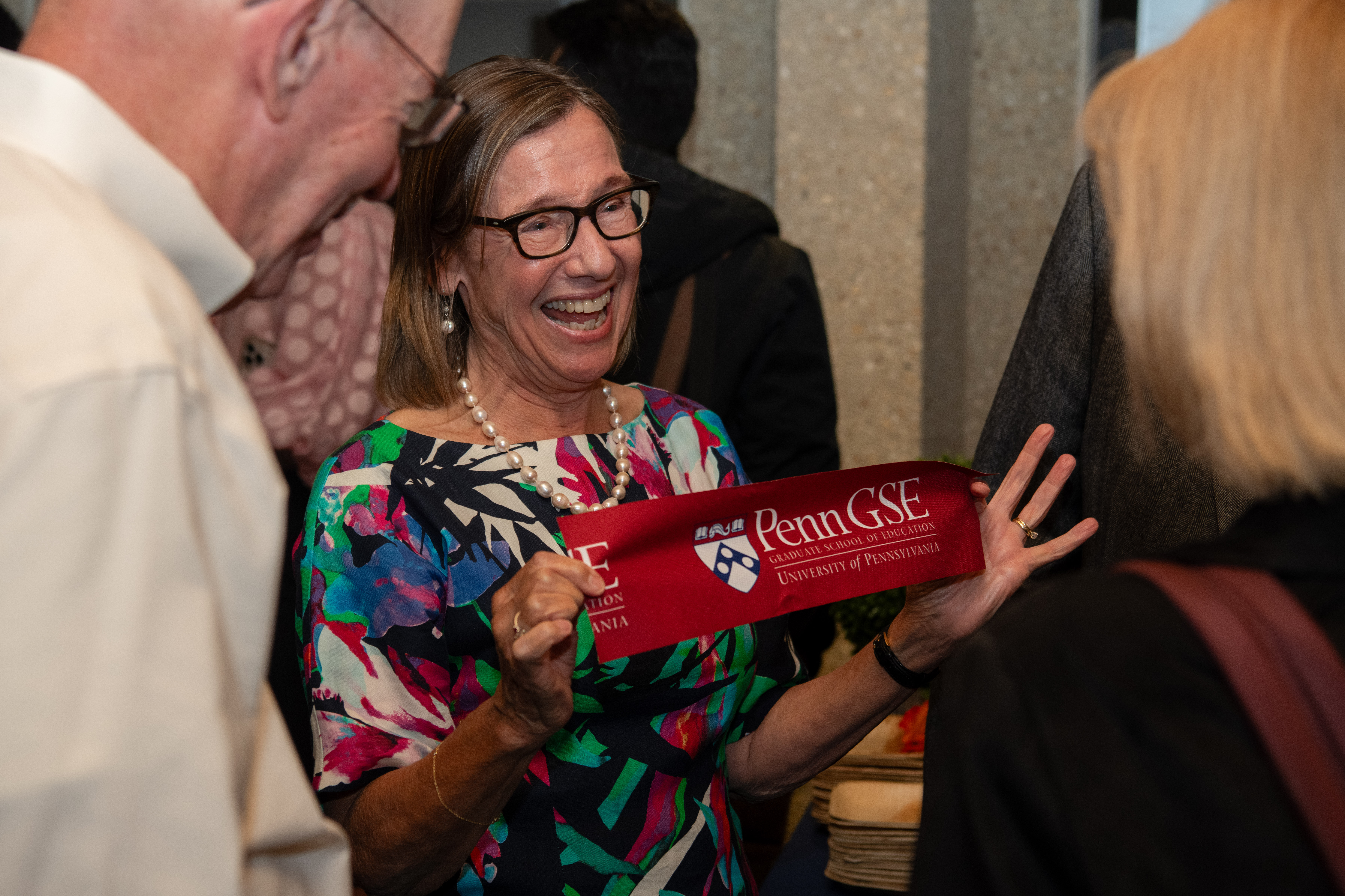 Penn GSE dean Pam Grossman smiles holding a piece of ribbon.