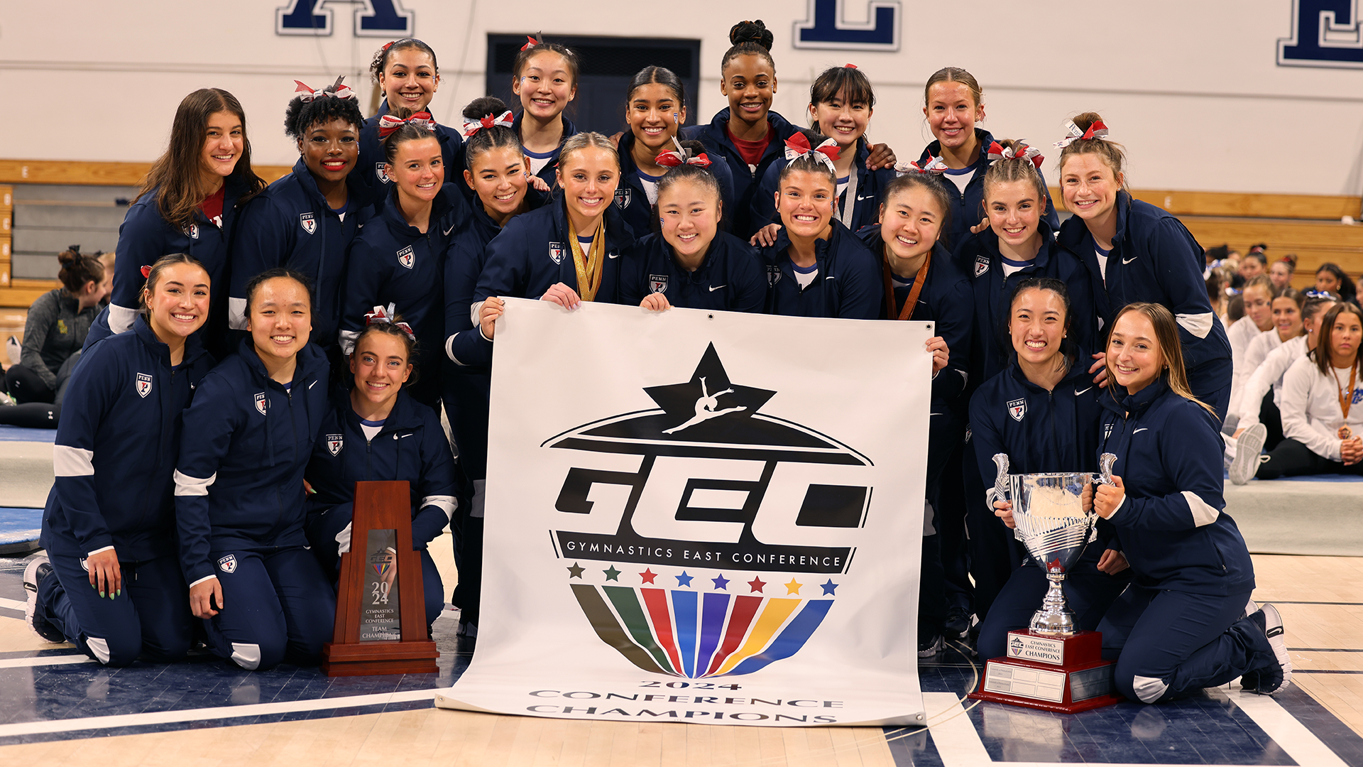Members of the gymnastics team pose with the championship banner after the GEC Championships.
