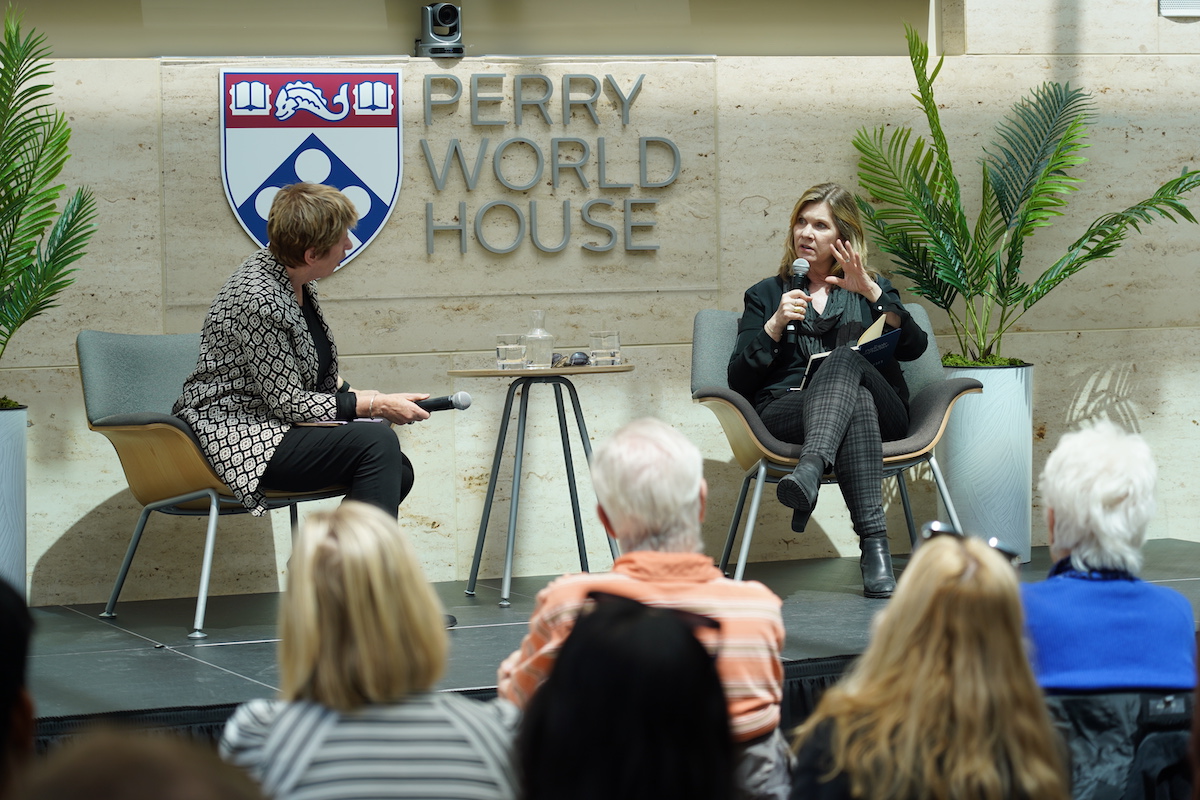 Kate Gilmore looks at Sarah Banet-Weiser, who is gesturing while speaking into a microphone on the stage at Perry World House.