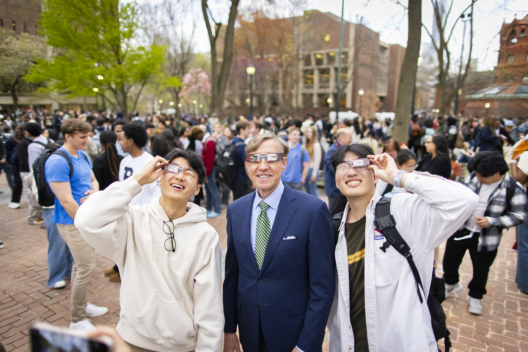 Penn president J. Larry Jameson and other students in eclipse glasses on Locust Walk during the solar eclipse.