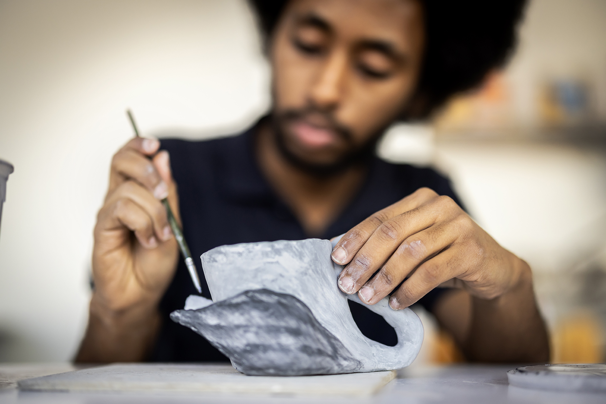a student works with clay and a paintbrush