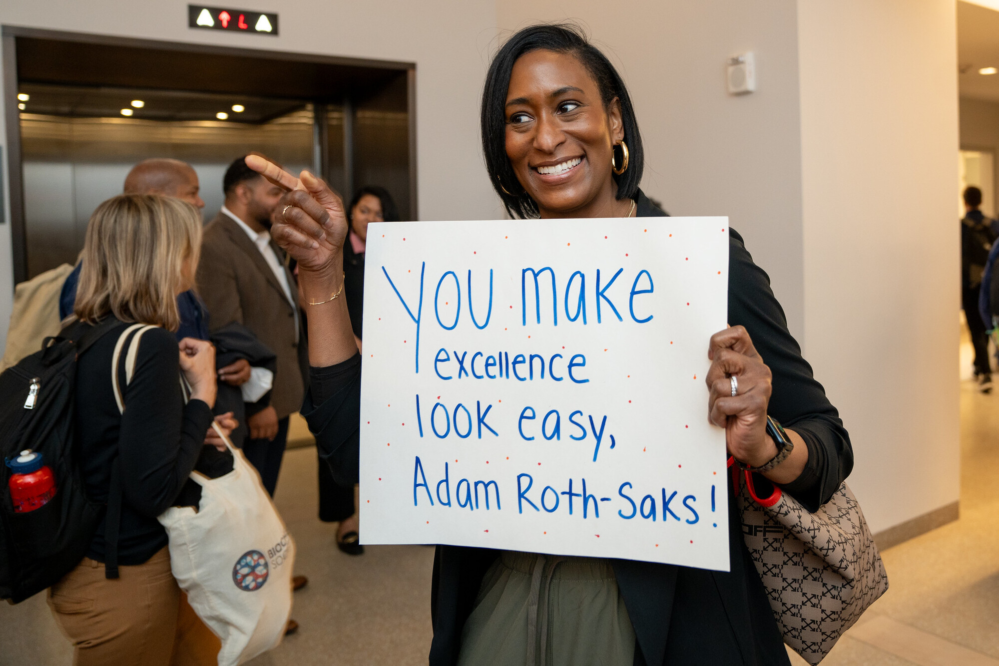 Sign being held that reads: "You Make Excellence look easy, Adam Roth-Saks!"