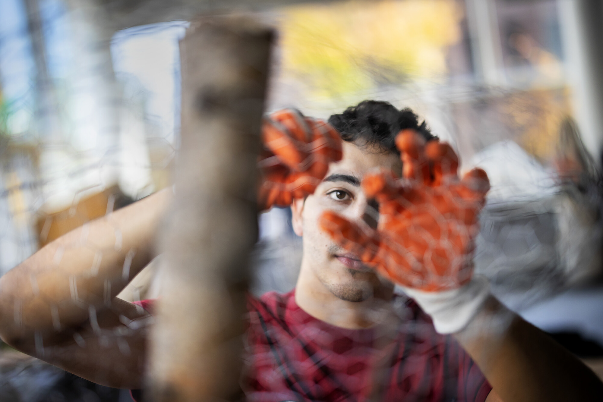 student with red gloves working with chicken wire