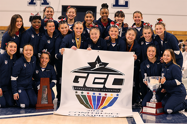 Members of the gymnastics team pose with the championship banner after the GEC Championships.