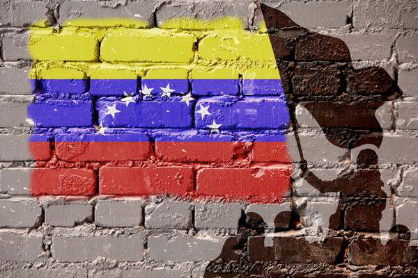 Venezuelan flag painted on wall with images of protesters in silhouette