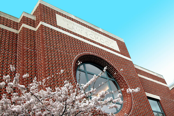 Brick facade of law school building with blue sky and cherry blossoms.