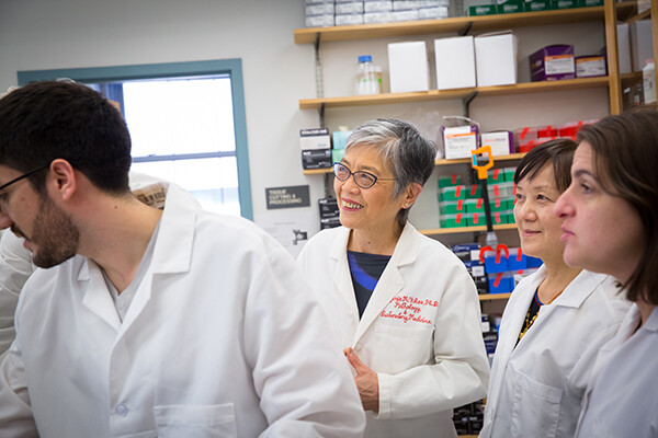 Virginia Lee stands smiling in a lab surrounded by three colleagues