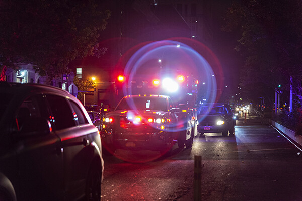 Ambulance with lights flashing on city street at night.