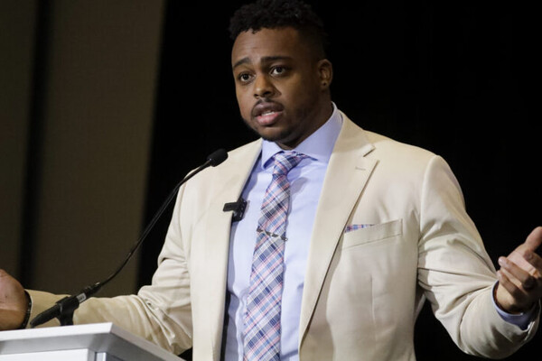 Wearing a suit and tie, Brandon Copeland speaks at the NFLPA Awards, where he received the Alan Page Award.
