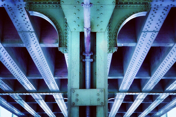 The underside of a bridge, with blue, purple, and teal greens visible. 