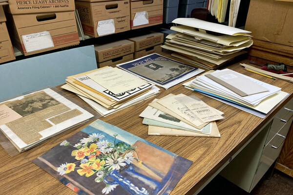A table in the archives office with an old painting, historic newspaper clippings, and old pamphlets from Penn Medicine archives.