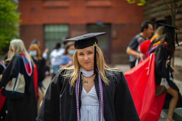 Student standing outside wearing graduation cap and gown