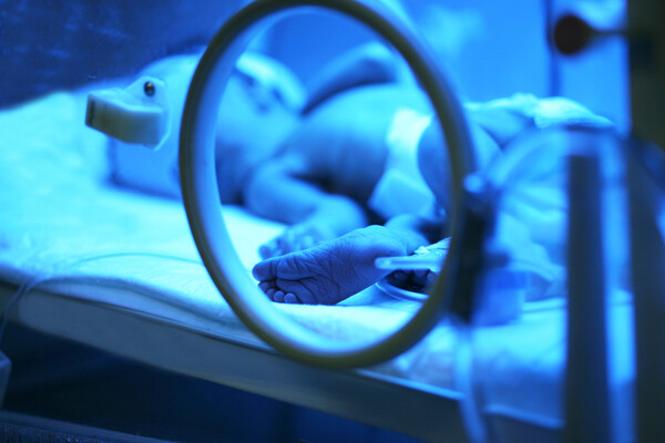 Newborn baby laying in an incubator.