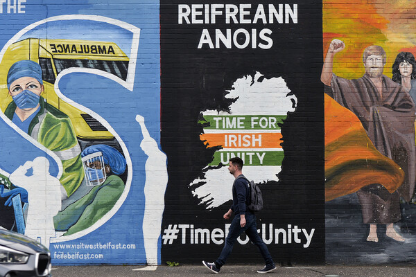 A man walks past graffiti about Irish unification on a wall in Belfast. 